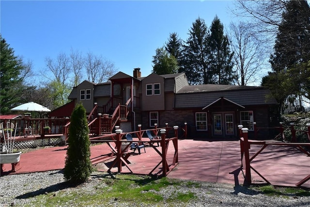 rear view of property featuring a patio, french doors, a chimney, and a deck