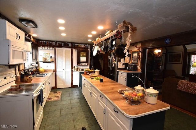 kitchen featuring butcher block countertops, a sink, white appliances, white cabinets, and dark tile patterned flooring