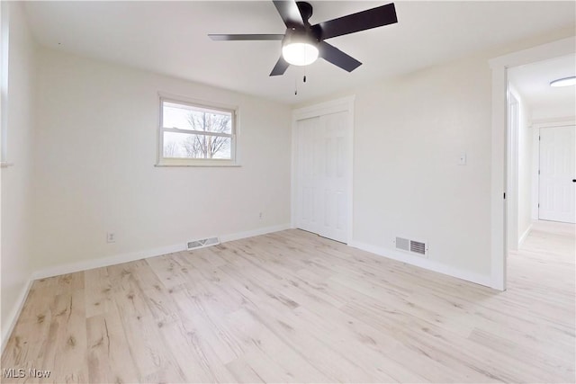 unfurnished room with visible vents, wood finished floors, and a ceiling fan