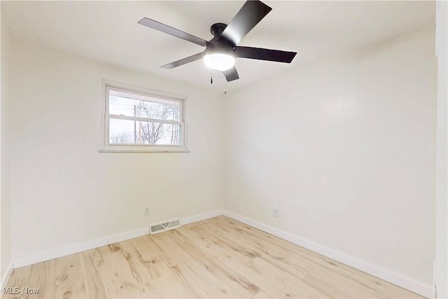 unfurnished room featuring baseboards, visible vents, and wood finished floors