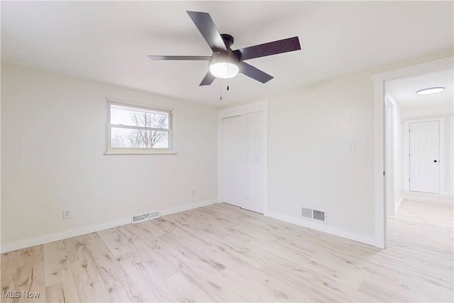 empty room featuring wood finished floors, visible vents, a ceiling fan, and baseboards