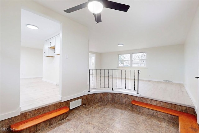 interior space with a ceiling fan, visible vents, and baseboards