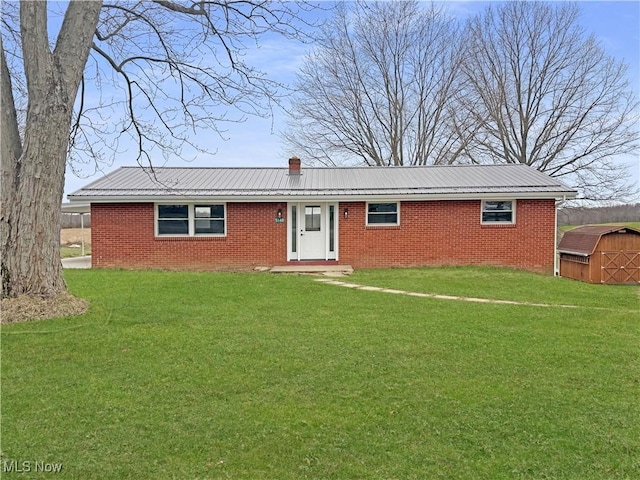 ranch-style house with a chimney, brick siding, and a front yard