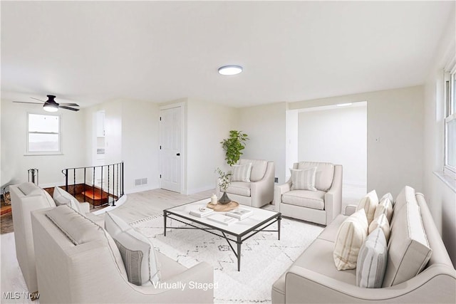 living room featuring baseboards, visible vents, wood finished floors, and ceiling fan