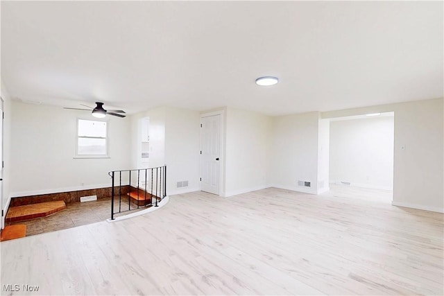 spare room featuring baseboards, visible vents, a ceiling fan, and light wood-style flooring