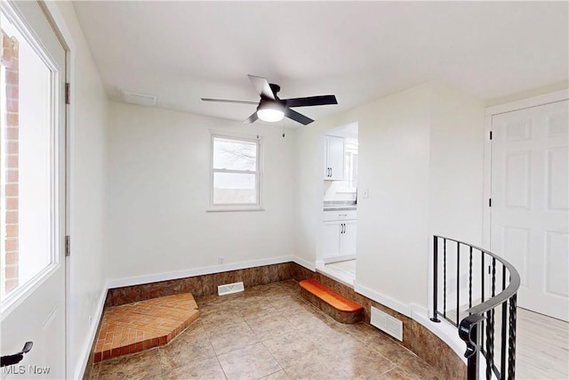 interior space featuring baseboards, visible vents, and a ceiling fan