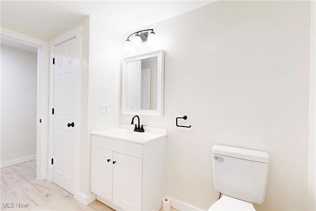 half bathroom featuring baseboards, marble finish floor, toilet, and vanity