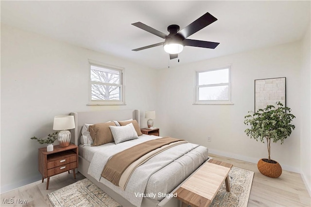 bedroom with ceiling fan, baseboards, and light wood-style floors