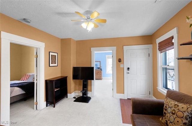 living room featuring baseboards, light carpet, and a ceiling fan