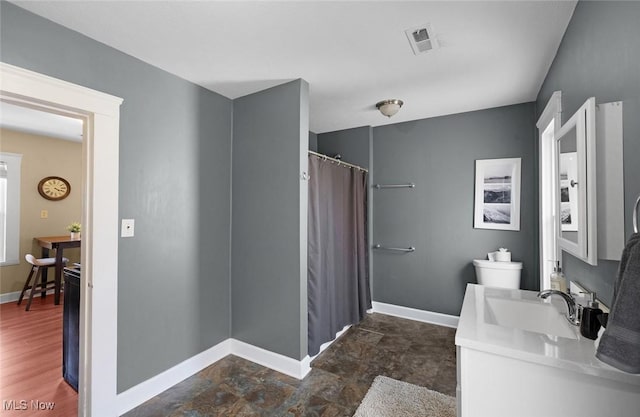 full bathroom featuring stone finish flooring, a shower with shower curtain, vanity, baseboards, and visible vents