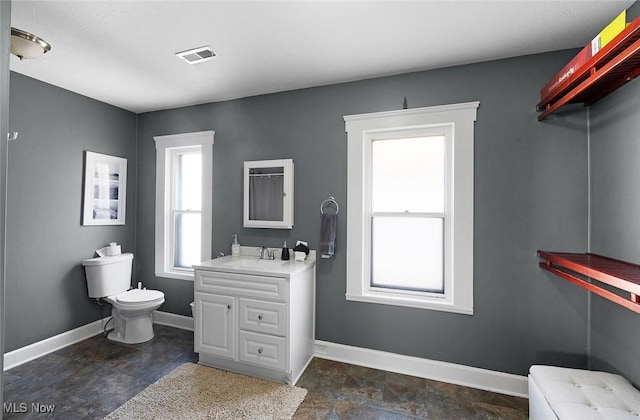 bathroom with stone finish floor, visible vents, toilet, and baseboards