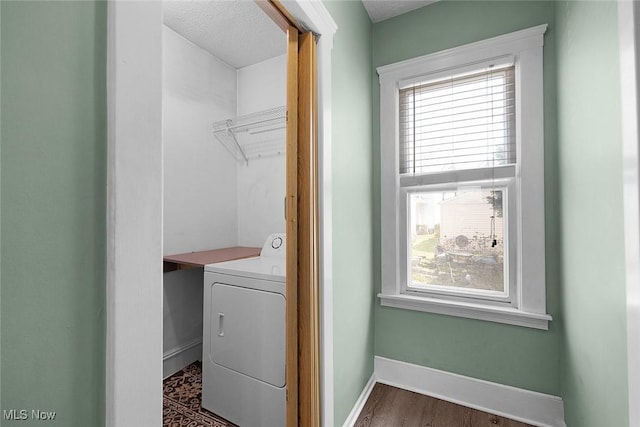 clothes washing area featuring dark wood-type flooring, washer / dryer, laundry area, and baseboards