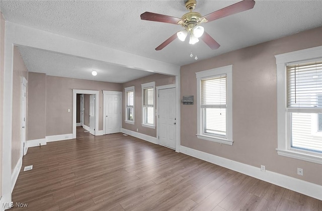 interior space featuring dark wood-style flooring, a ceiling fan, and baseboards