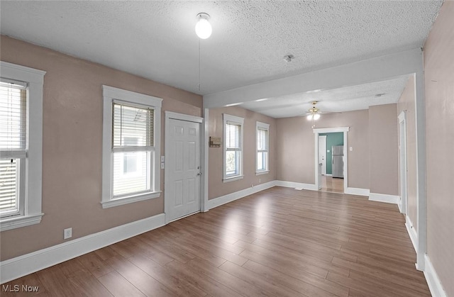 foyer with a textured ceiling, a ceiling fan, wood finished floors, and baseboards