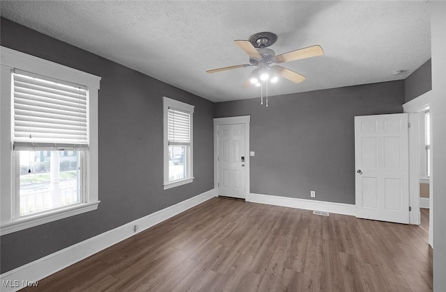 spare room with wood finished floors, a ceiling fan, and a textured ceiling