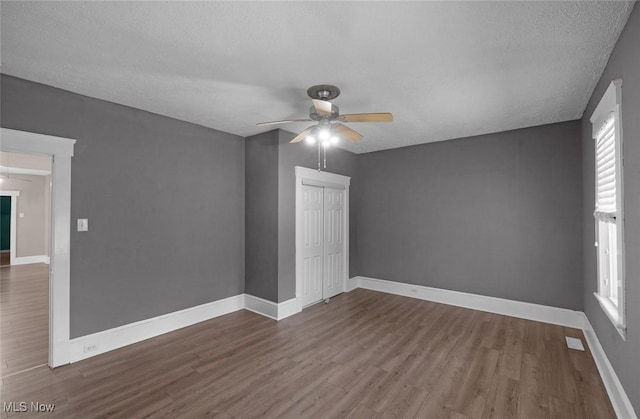 unfurnished room featuring wood finished floors, ceiling fan, baseboards, and a textured ceiling