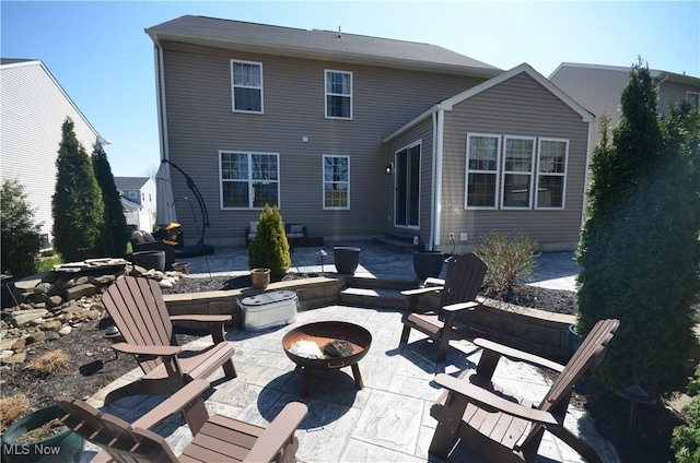 back of house with an outdoor fire pit and a patio