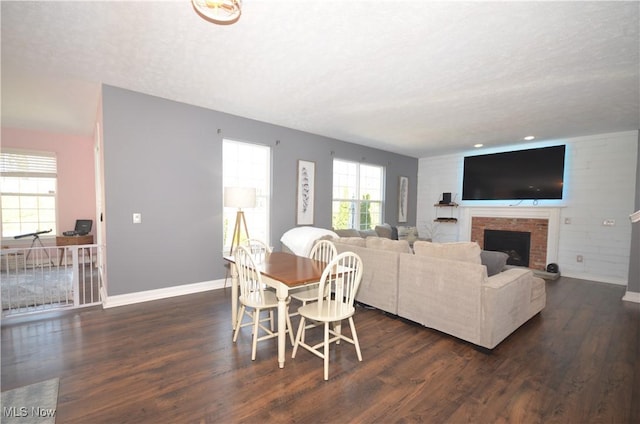 living room featuring a brick fireplace, dark wood-style floors, and baseboards