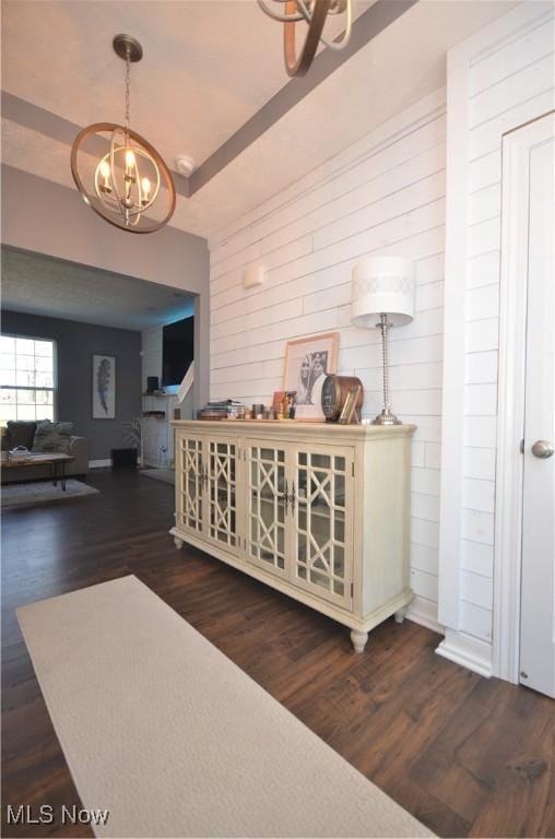 corridor with wood walls, wood finished floors, and a chandelier