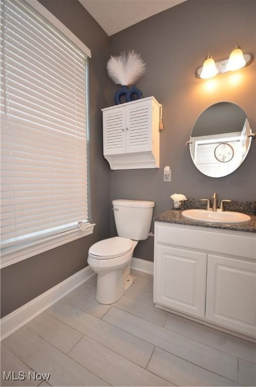 bathroom featuring vanity, toilet, and baseboards