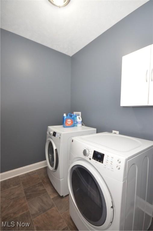 laundry room with stone finish flooring, washer and clothes dryer, cabinet space, and baseboards