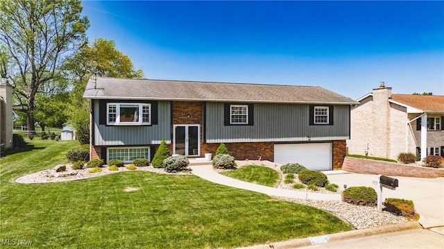 bi-level home featuring driveway, an attached garage, a front yard, and brick siding
