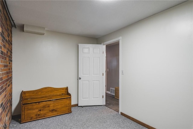 carpeted bedroom with baseboards, visible vents, and brick wall