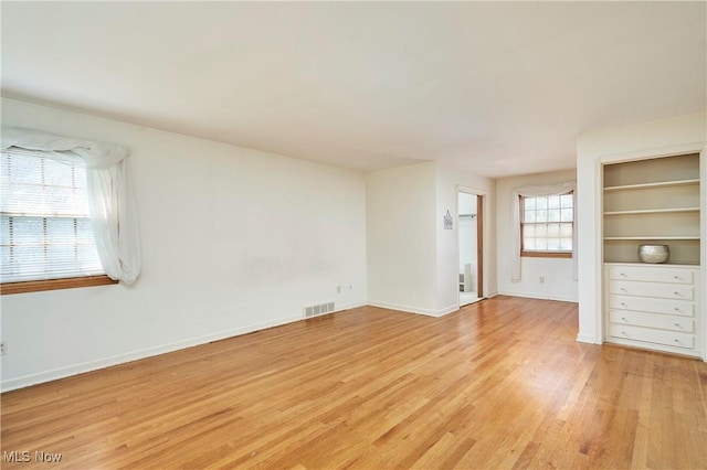 unfurnished room with visible vents, light wood-style flooring, and baseboards