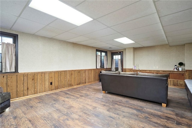 living area with dark wood-type flooring, a paneled ceiling, and plenty of natural light