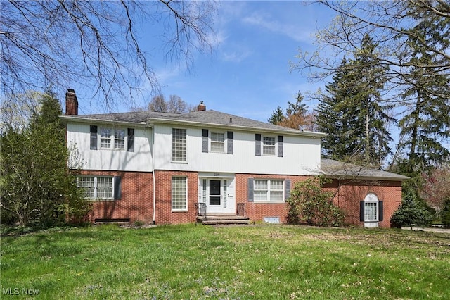 back of property featuring brick siding, a lawn, and a chimney