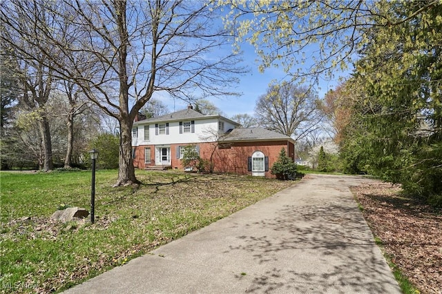 view of front of home featuring brick siding, a front yard, and concrete driveway