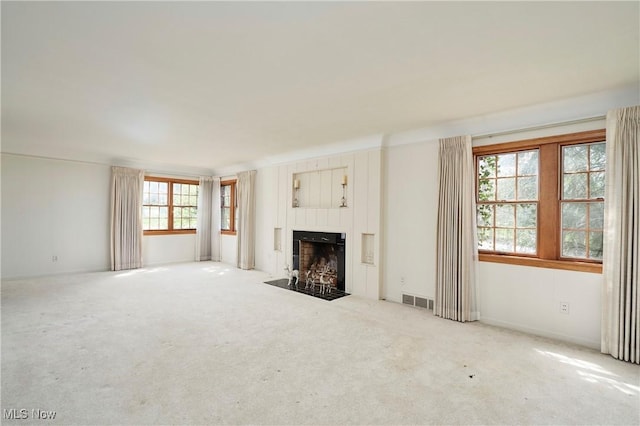 unfurnished living room with visible vents, a fireplace with flush hearth, and carpet flooring