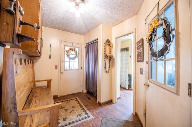 mudroom with a textured ceiling, wood finished floors, and baseboards