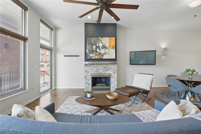 living room with a ceiling fan, visible vents, wood finished floors, and baseboards