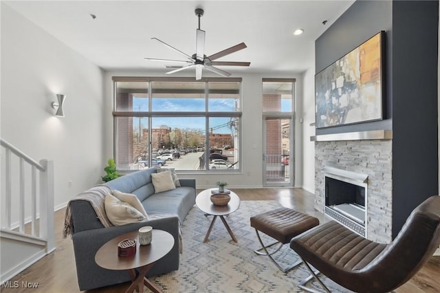 living area with baseboards, stairway, wood finished floors, and ceiling fan