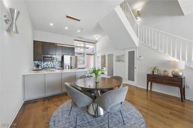 dining space featuring dark wood-style flooring, recessed lighting, baseboards, and stairs