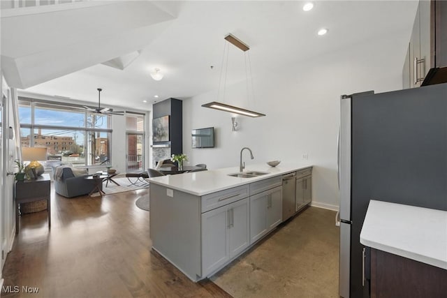 kitchen featuring a sink, appliances with stainless steel finishes, ceiling fan, open floor plan, and a peninsula