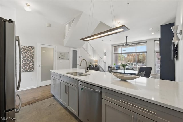 kitchen with a sink, appliances with stainless steel finishes, light countertops, open floor plan, and gray cabinets