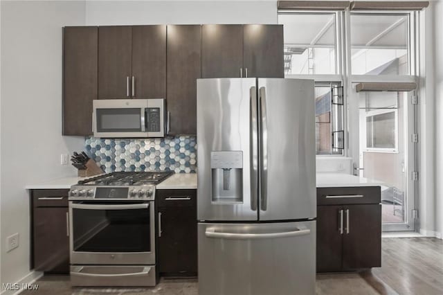 kitchen featuring dark brown cabinets, appliances with stainless steel finishes, light countertops, and plenty of natural light