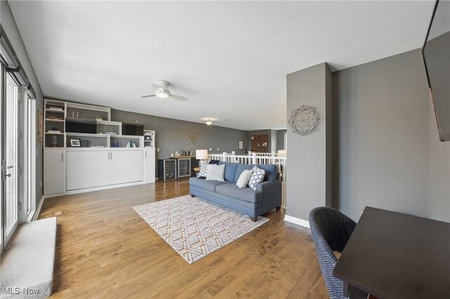 living area featuring wood finished floors, ceiling fan, and baseboards
