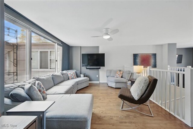 living room with a ceiling fan, wood finished floors, and baseboards