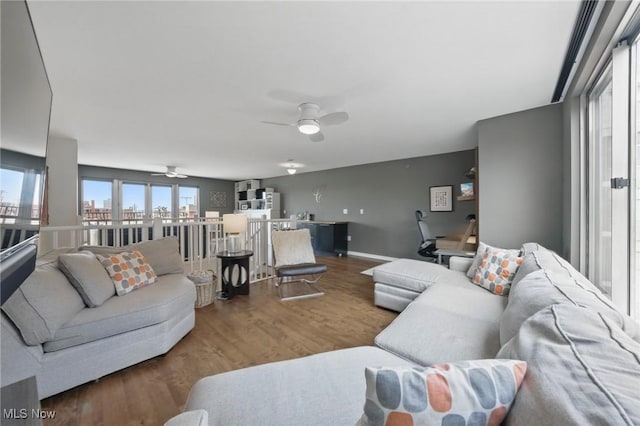 living area with a ceiling fan, wood finished floors, and baseboards