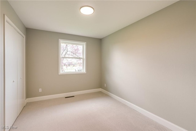 unfurnished bedroom with light colored carpet, visible vents, baseboards, and a closet