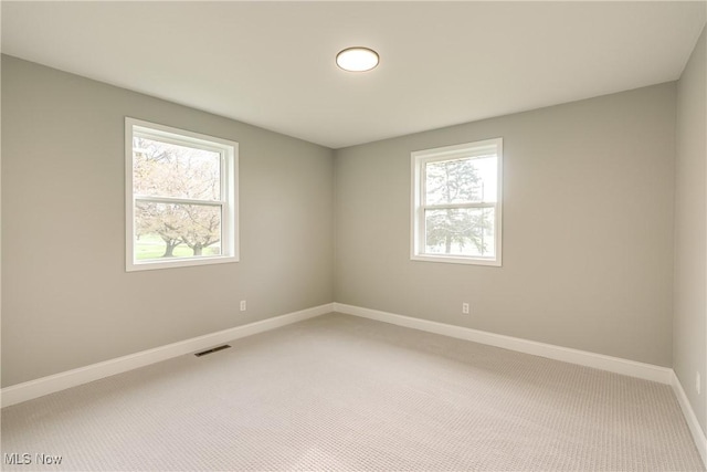 unfurnished room with carpet, visible vents, and baseboards