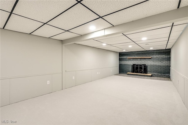 finished basement featuring a paneled ceiling, recessed lighting, carpet flooring, and a wood stove
