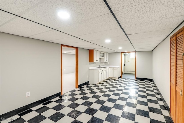 below grade area featuring tile patterned floors, a baseboard radiator, recessed lighting, and a sink