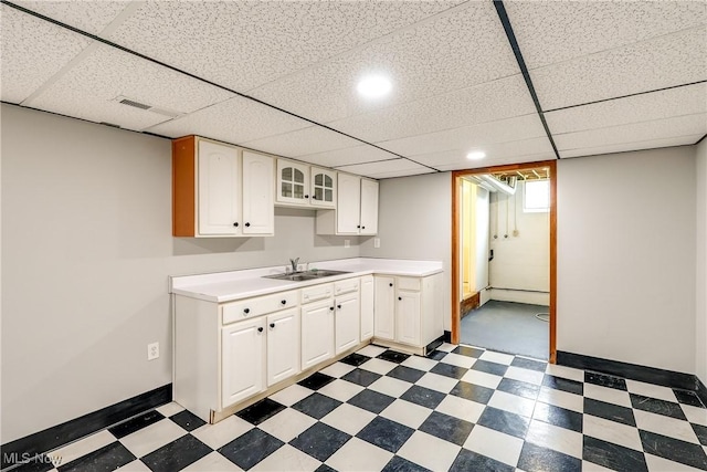 kitchen with a baseboard heating unit, a sink, dark floors, white cabinetry, and light countertops