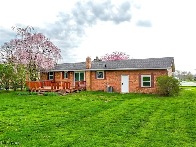 rear view of property featuring a chimney, brick siding, and a lawn