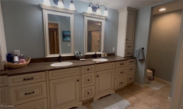 bathroom featuring toilet, tile patterned flooring, a sink, and double vanity