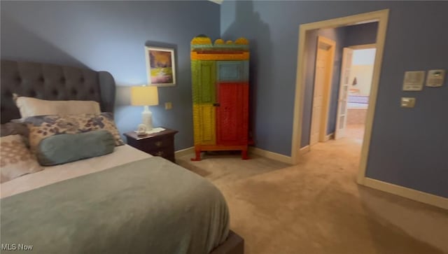 bedroom featuring light carpet and baseboards